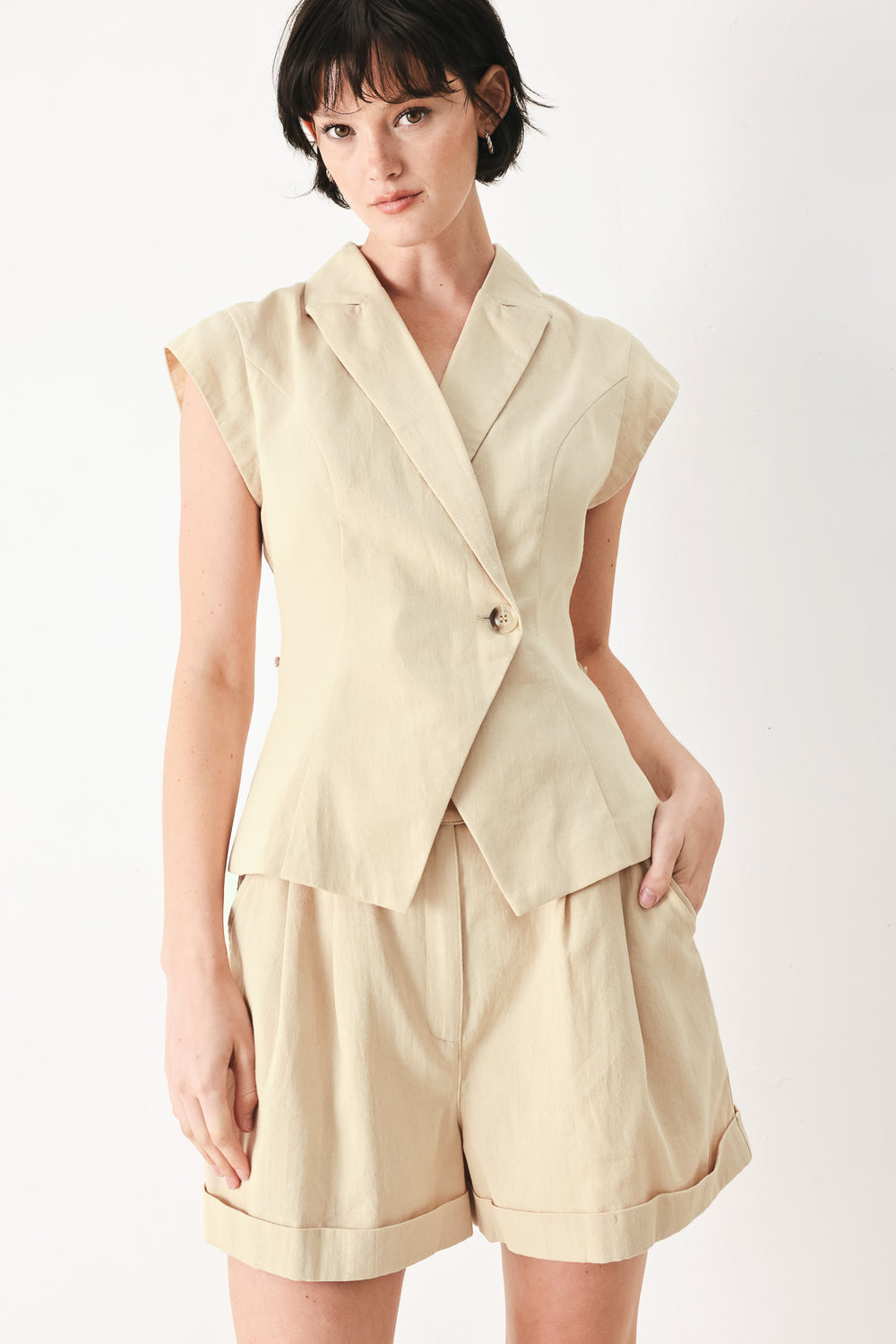 Woman wearing light tan woven vest with collar, cap sleeve and button closure | FREEMARKET