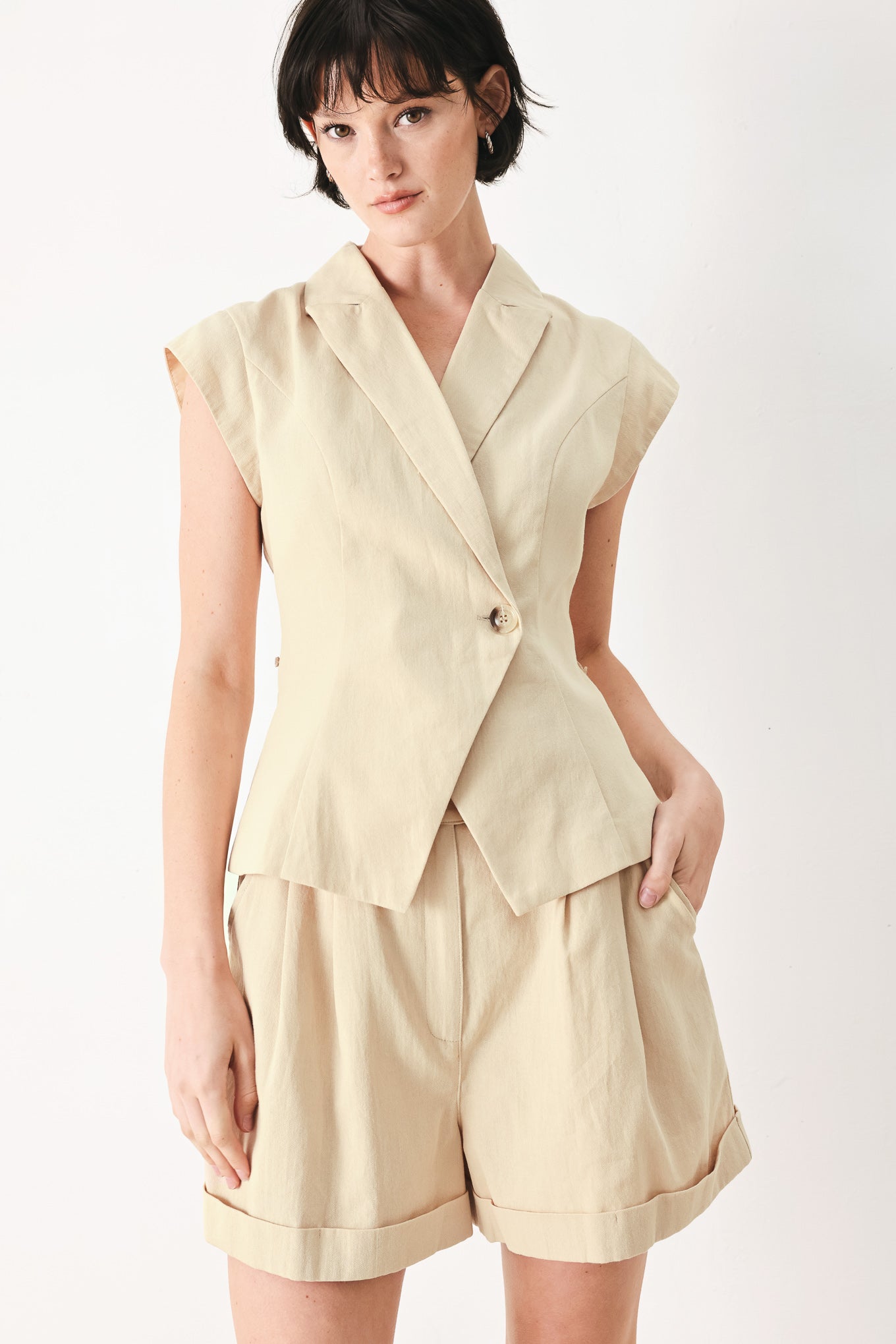 Woman wearing light tan woven vest with collar, cap sleeve and button closure | FREEMARKET