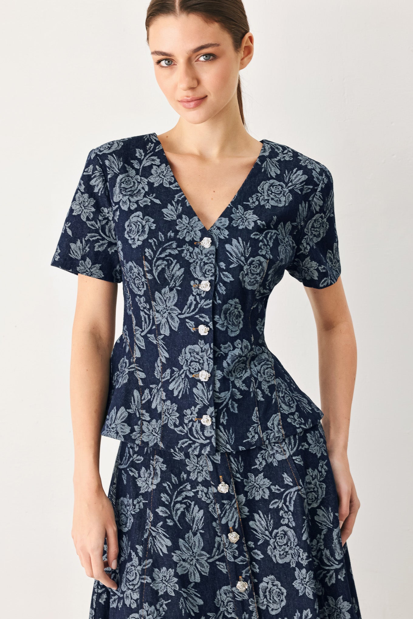Woman wearing a denim woven jacquard top with V neckline, short sleeve, front button down and peplum | FREEMARKET