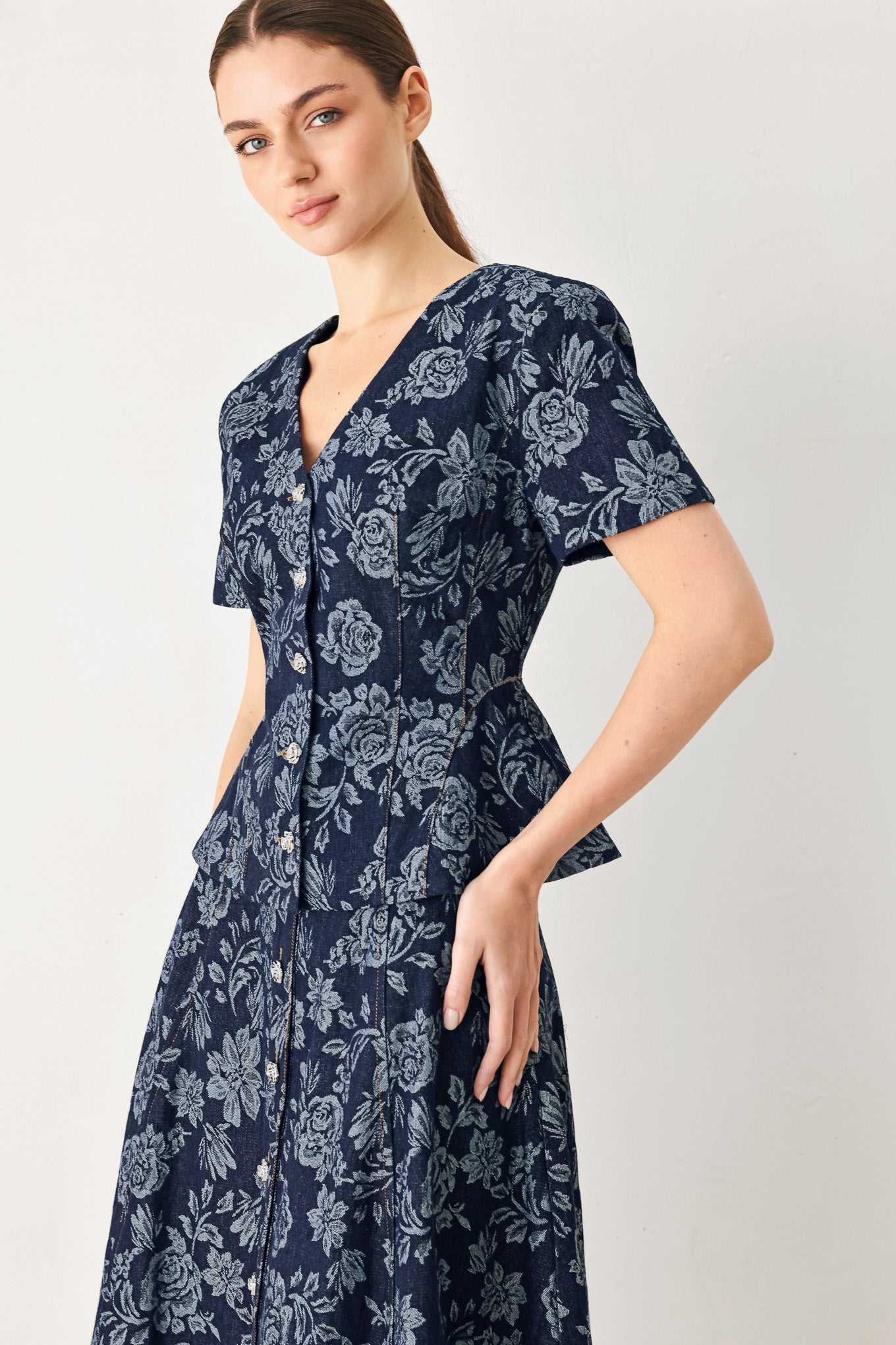 Woman wearing a denim woven jacquard top with V neckline, short sleeve, front button down and peplum | FREEMARKET