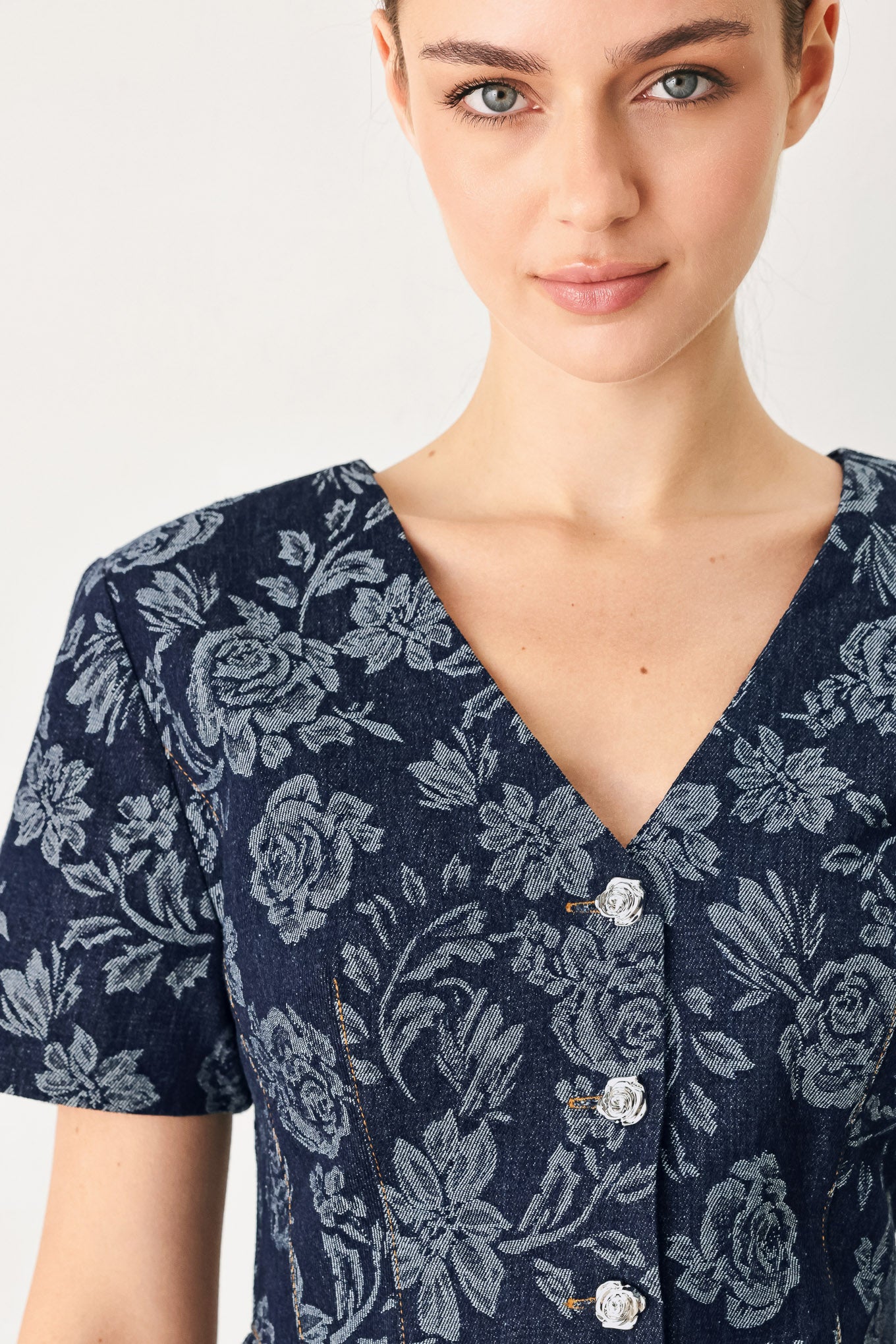Woman wearing a denim woven jacquard top with V neckline, short sleeve, front button down and peplum | FREEMARKET
