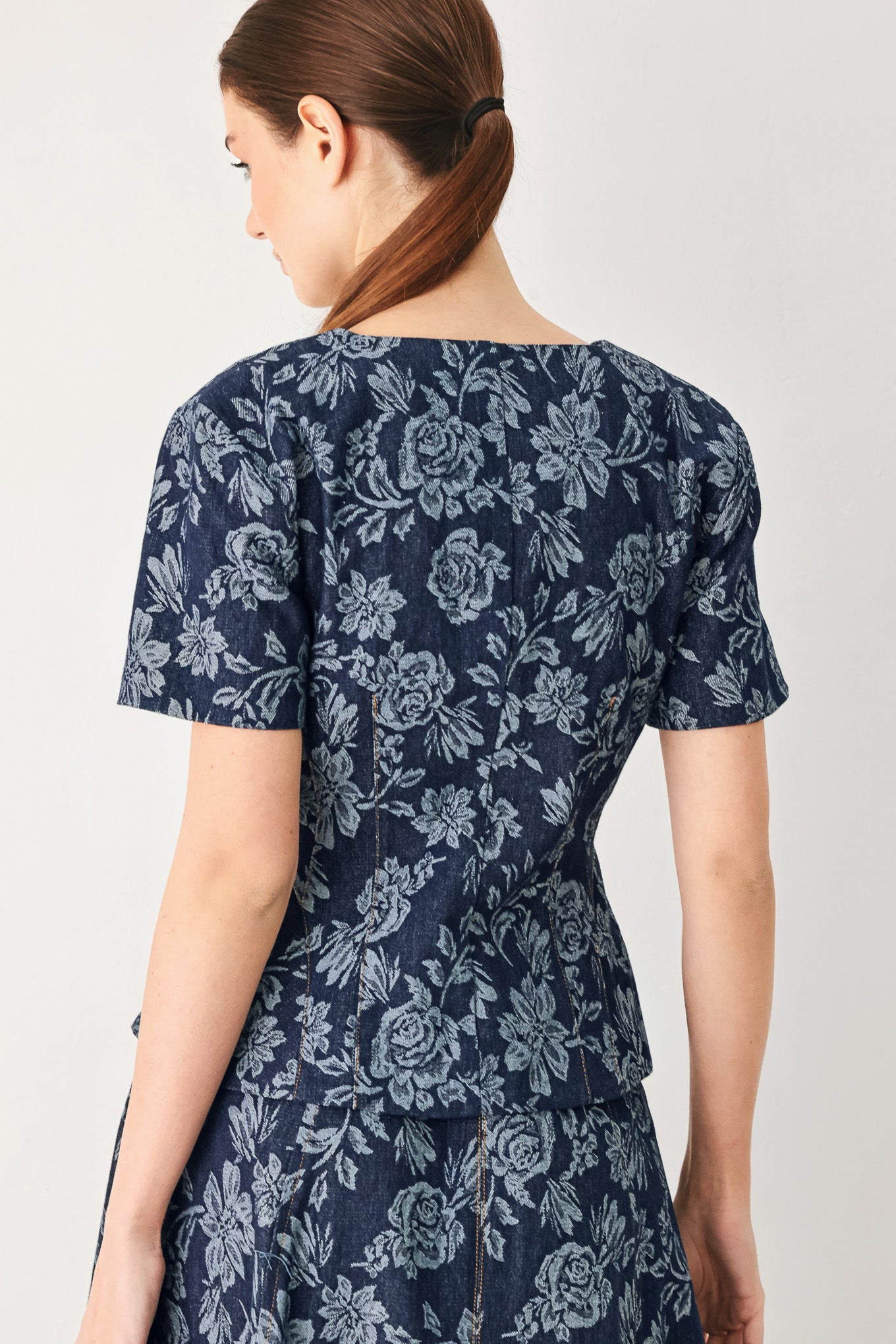 Woman wearing a denim woven jacquard top with V neckline, short sleeve, front button down and peplum | FREEMARKET