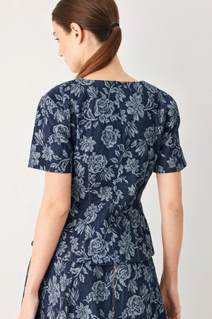 Woman wearing a denim woven jacquard top with V neckline, short sleeve, front button down and peplum | FREEMARKET