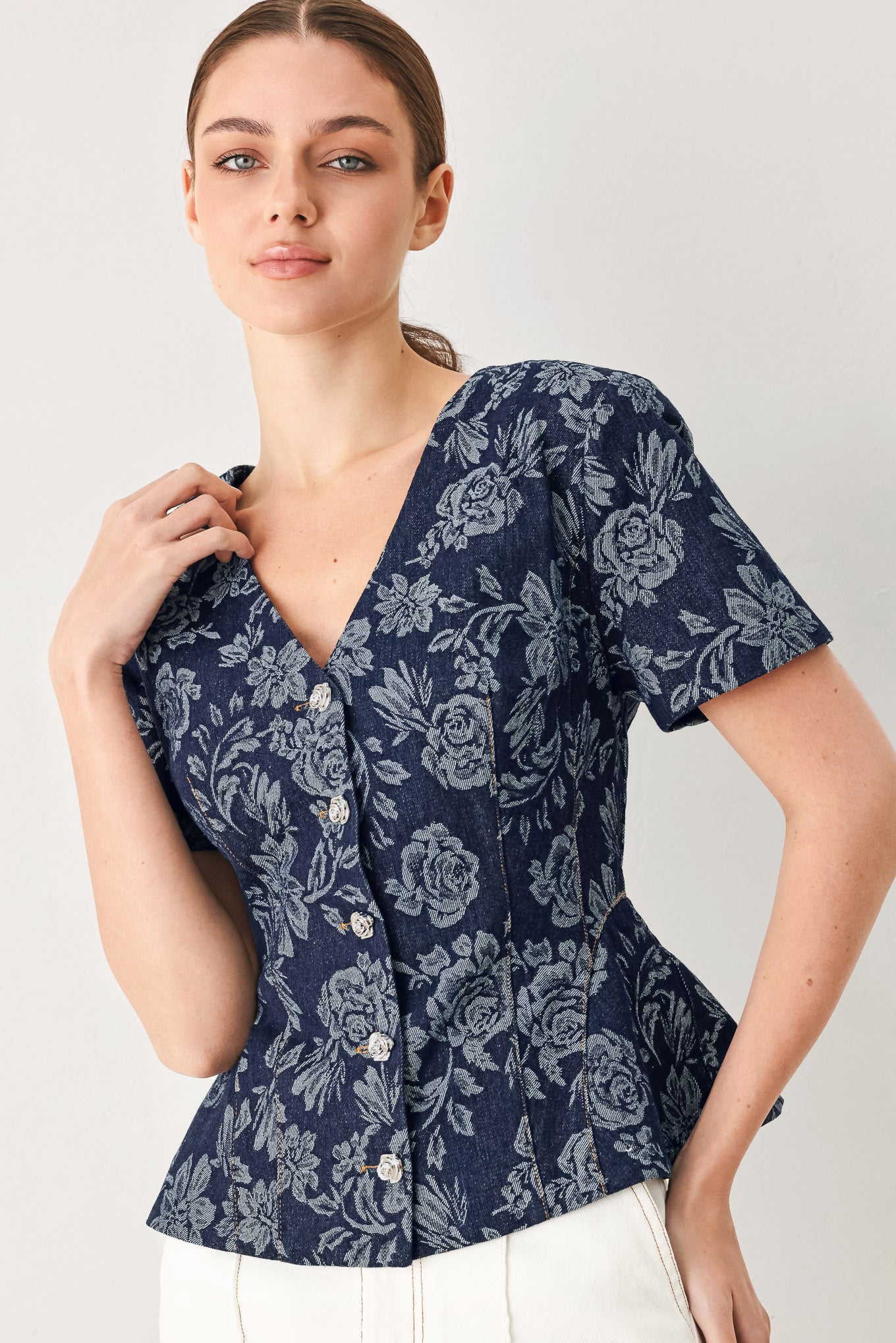 Woman wearing a denim woven jacquard top with V neckline, short sleeve, front button down and peplum | FREEMARKET