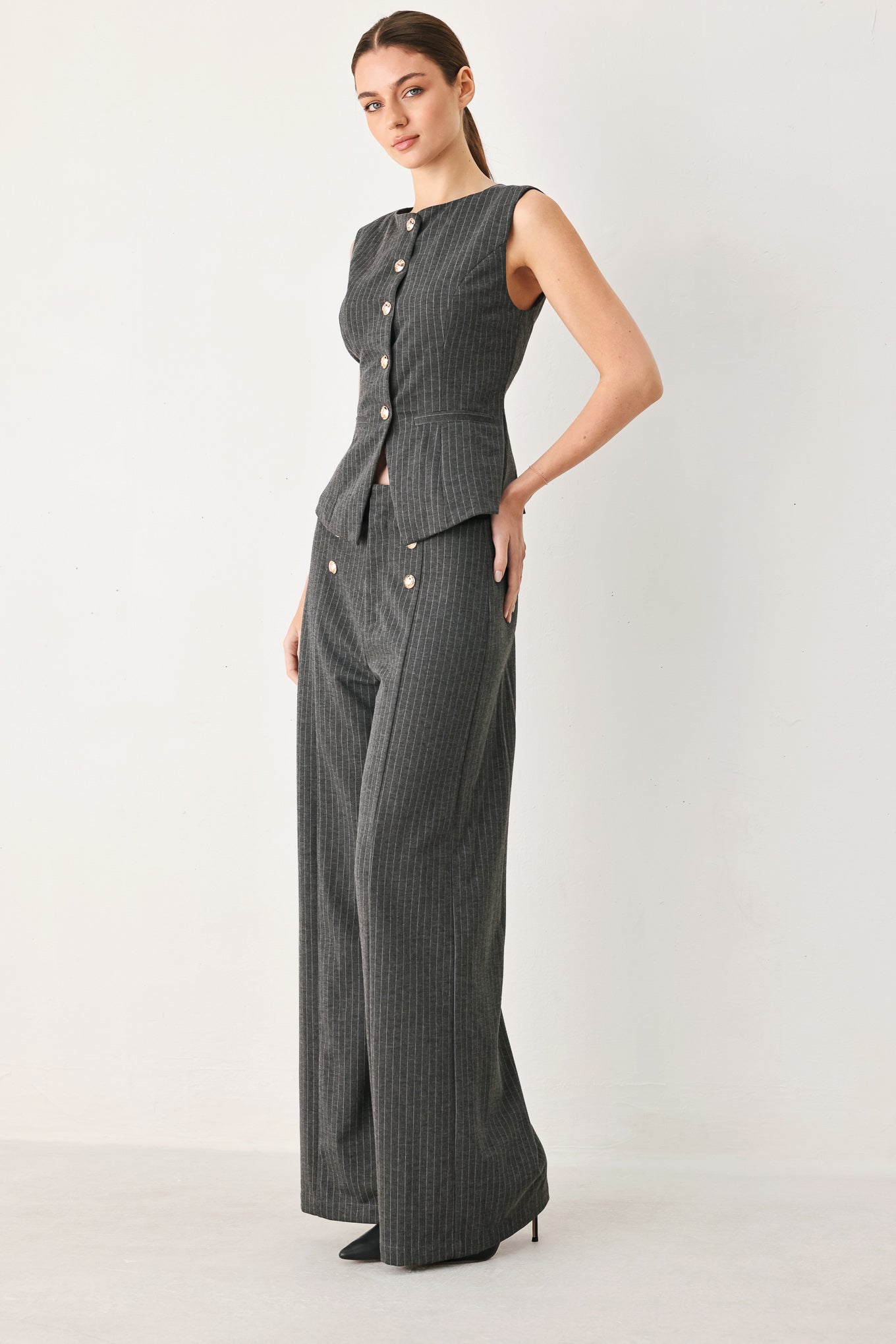 Woman wearing a charcoal and white striped stretch woven vest with wide neckline, sleeveless and front button closure | FREEMARKET