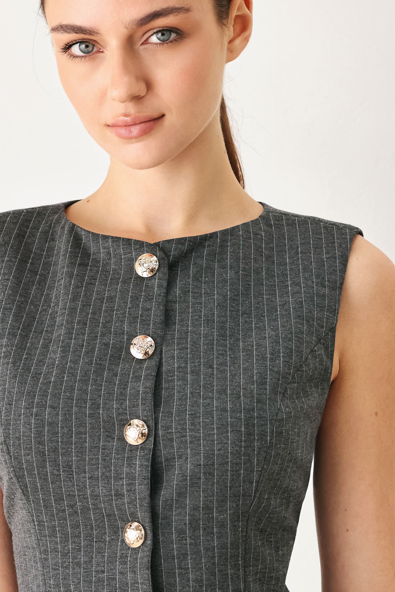 Woman wearing a charcoal and white striped stretch woven vest with wide neckline, sleeveless and front button closure | FREEMARKET
