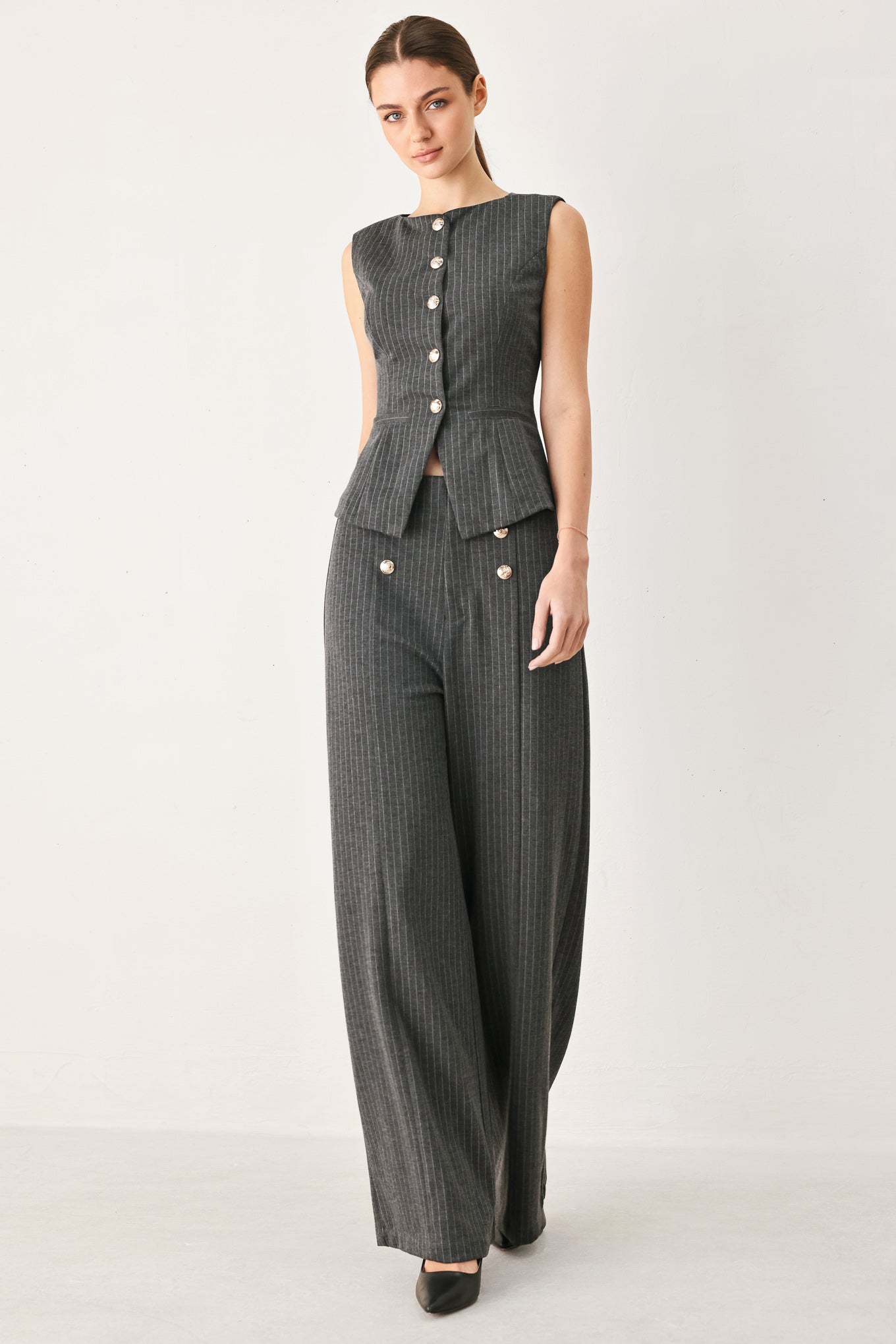Woman wearing a charcoal and white striped stretch woven vest with wide neckline, sleeveless and front button closure | FREEMARKET