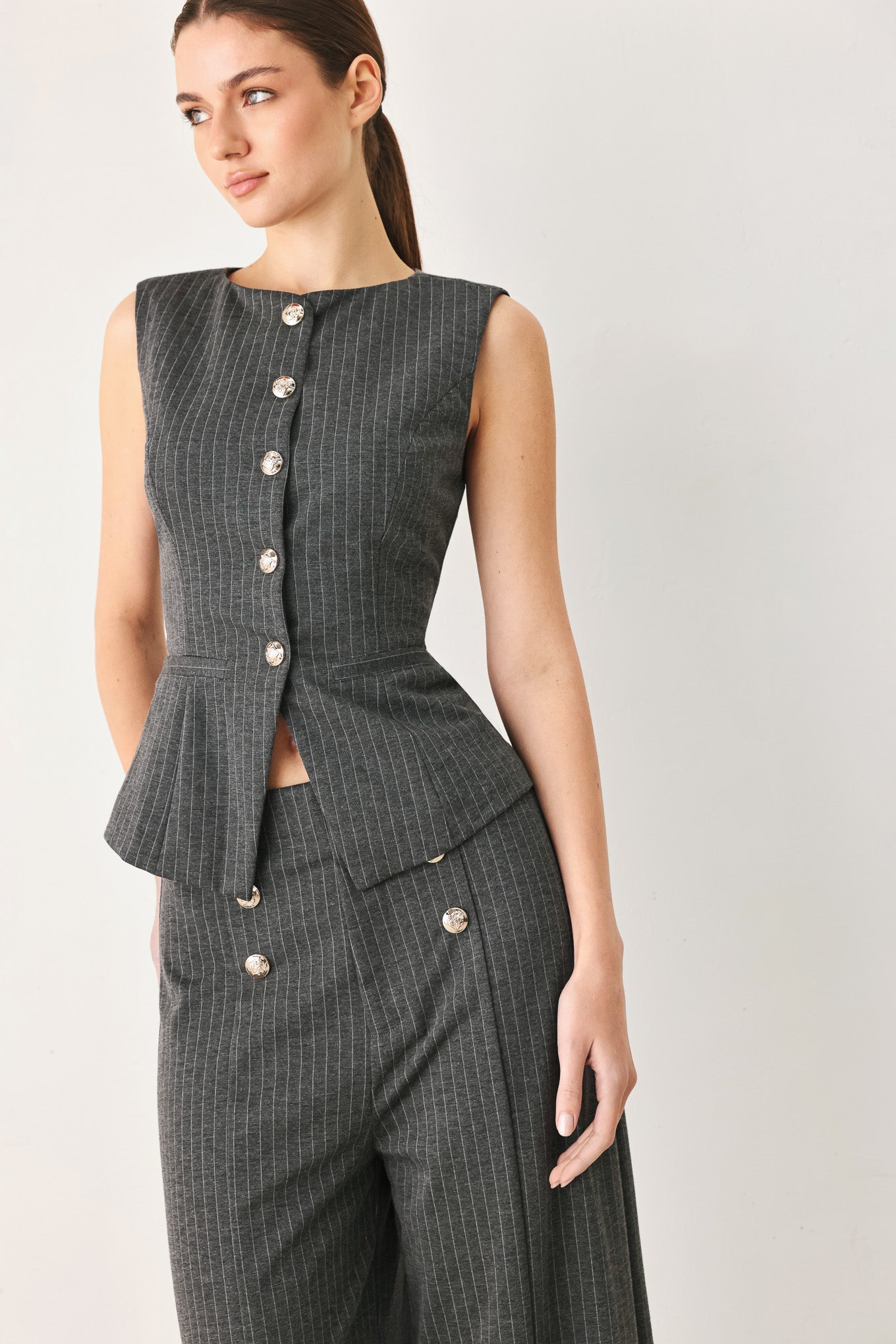 Woman wearing a charcoal and white striped stretch woven vest with wide neckline, sleeveless and front button closure | FREEMARKET