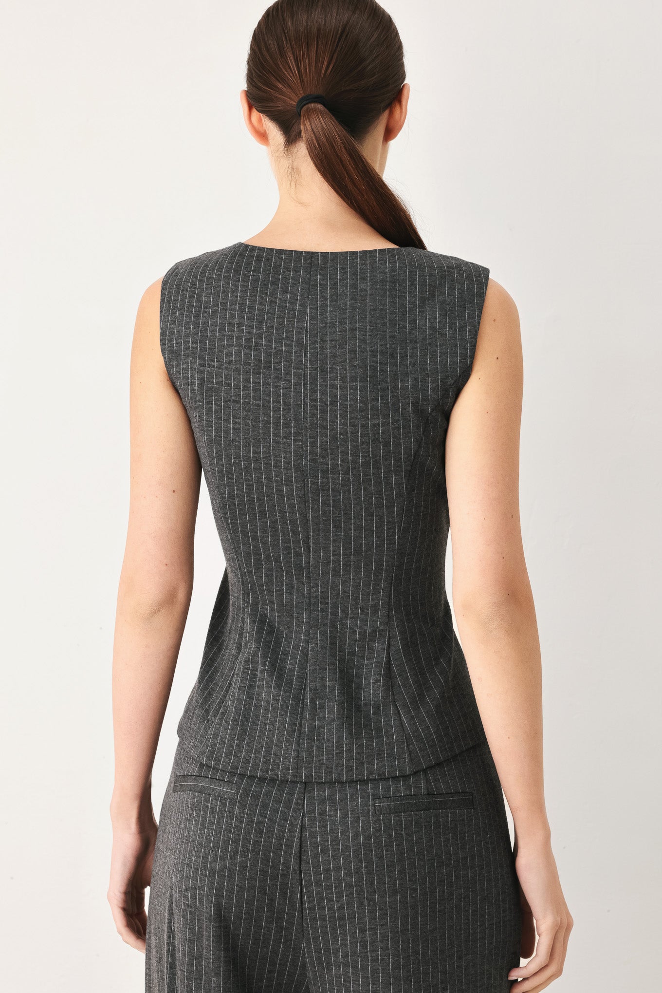 Woman wearing a charcoal and white striped stretch woven vest with wide neckline, sleeveless and front button closure | FREEMARKET