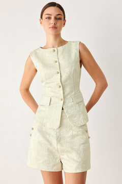 Woman wearing a sleeveless, button-front vest in a light cream or off-white jacquard fabric with small gold-tone buttons | FREEMARKET