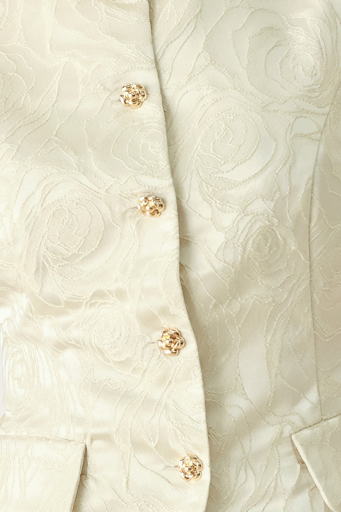 Woman wearing a sleeveless, button-front vest in a light cream or off-white jacquard fabric with small gold-tone buttons | FREEMARKET