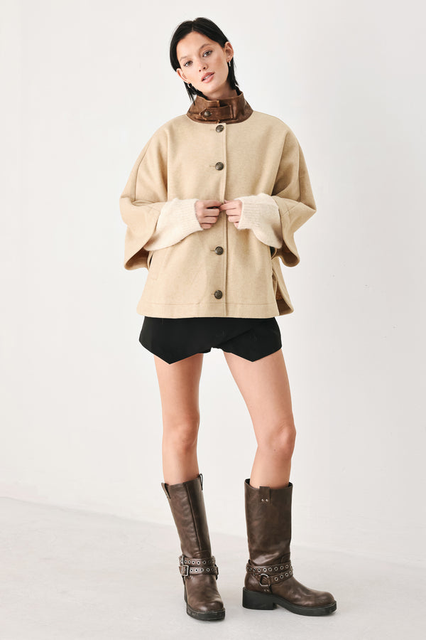 A model wearing a beige cropped cape jacket with a brown collar, buttoned front, and wide sleeves | FREEMARKET