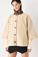 A model wearing a beige cropped cape jacket with a brown collar, buttoned front, and wide sleeves | FREEMARKET