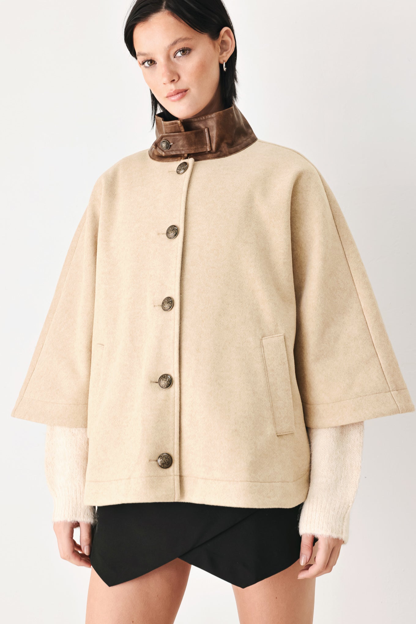 A model wearing a beige cropped cape jacket with a brown collar, buttoned front, and wide sleeves | FREEMARKET