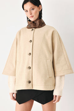 A model wearing a beige cropped cape jacket with a brown collar, buttoned front, and wide sleeves | FREEMARKET