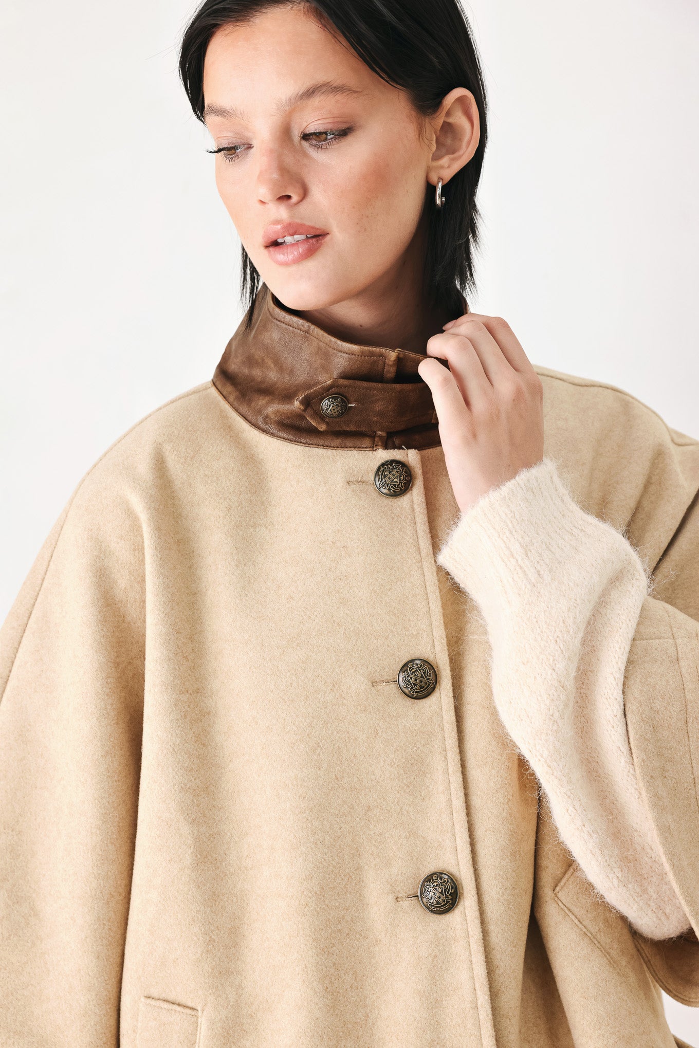 A model wearing a beige cropped cape jacket with a brown collar, buttoned front, and wide sleeves | FREEMARKET