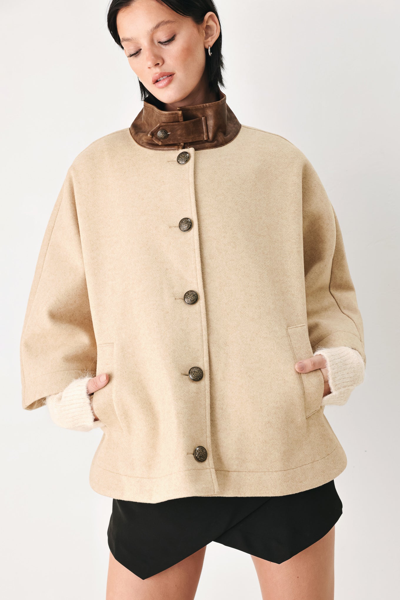 A model wearing a beige cropped cape jacket with a brown collar, buttoned front, and wide sleeves | FREEMARKET