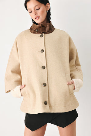 A model wearing a beige cropped cape jacket with a brown collar, buttoned front, and wide sleeves | FREEMARKET