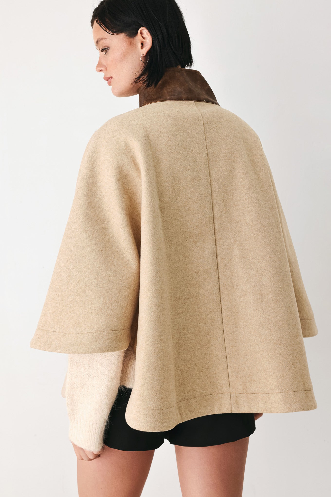 A model wearing a beige cropped cape jacket with a brown collar, buttoned front, and wide sleeves | FREEMARKET