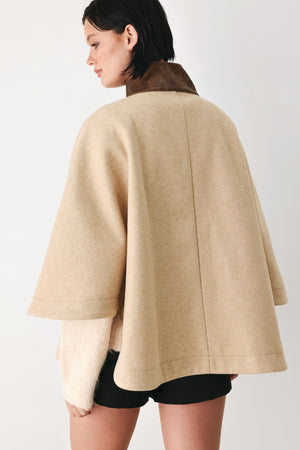 A model wearing a beige cropped cape jacket with a brown collar, buttoned front, and wide sleeves | FREEMARKET