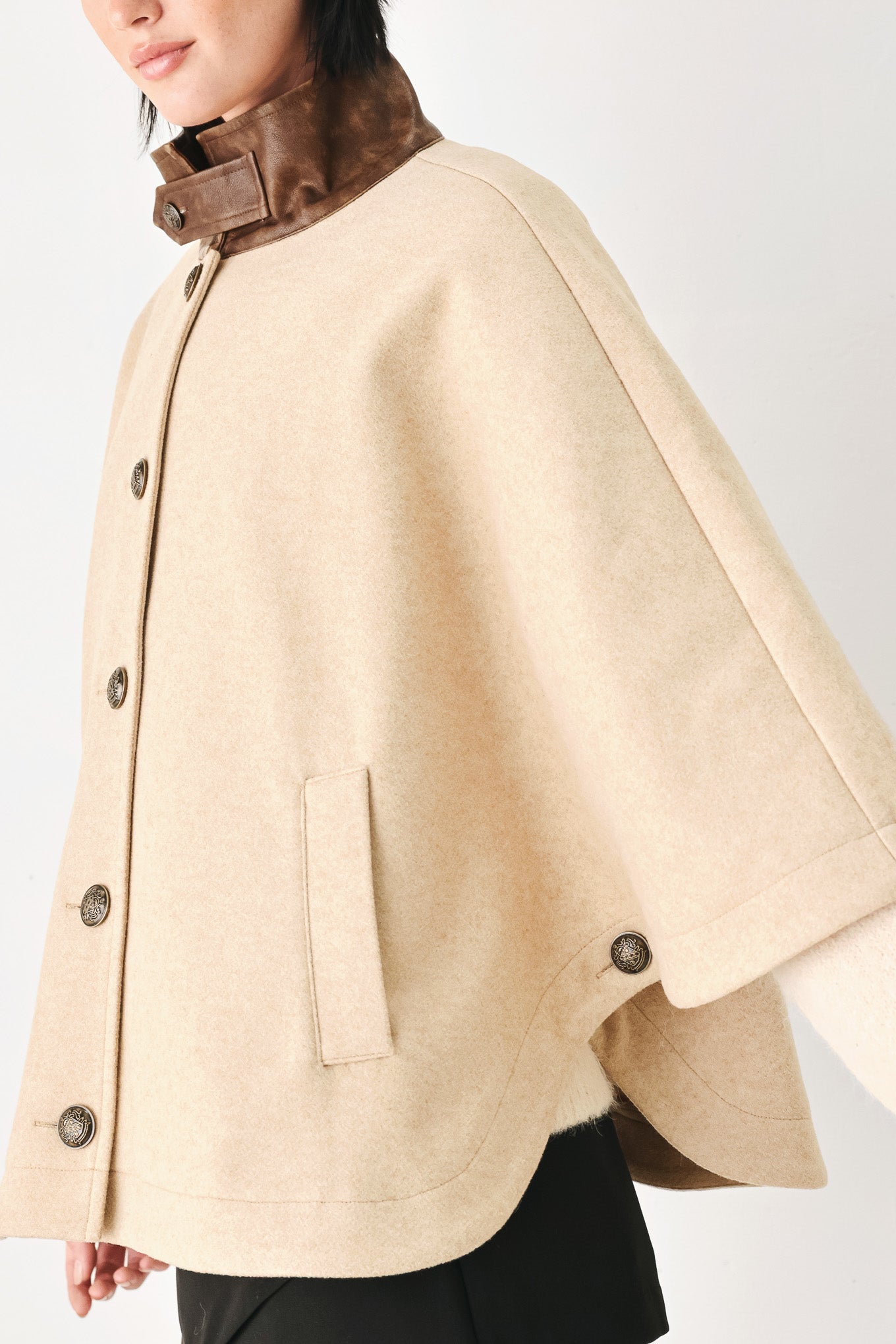 A model wearing a beige cropped cape jacket with a brown collar, buttoned front, and wide sleeves | FREEMARKET