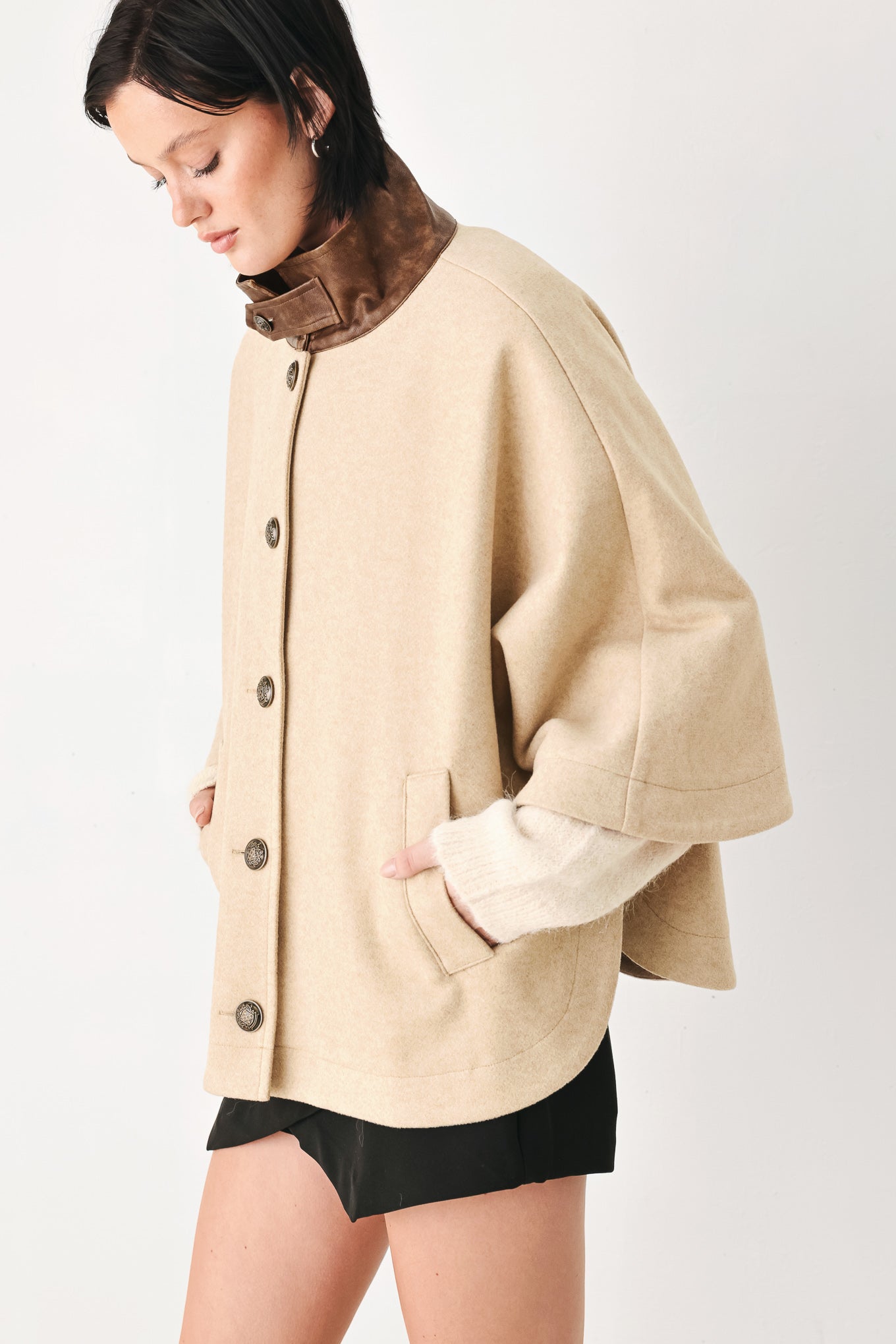 A model wearing a beige cropped cape jacket with a brown collar, buttoned front, and wide sleeves | FREEMARKET