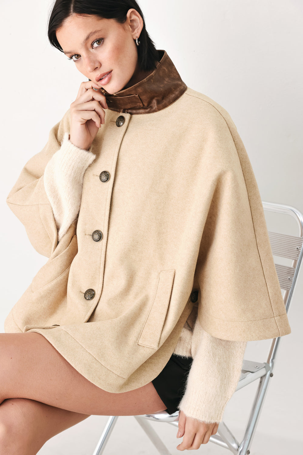 A model wearing a beige cropped cape jacket with a brown collar, buttoned front, and wide sleeves | FREEMARKET
