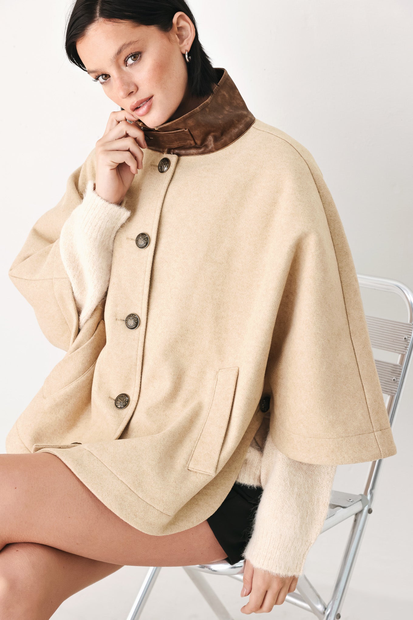 A model wearing a beige cropped cape jacket with a brown collar, buttoned front, and wide sleeves | FREEMARKET