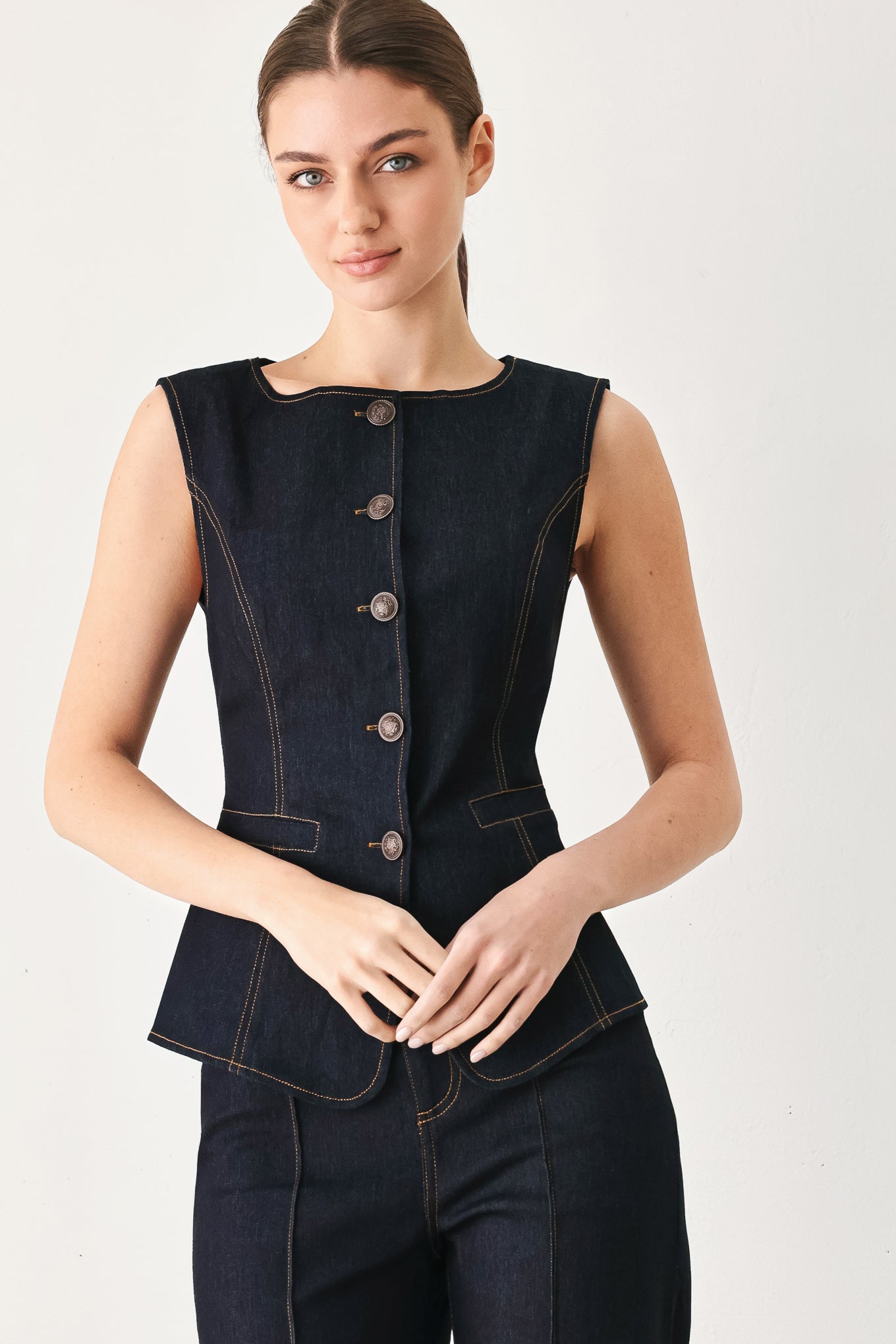 Woman wearing a dark denim vest with wide neckline and front button down | FREEMARKET