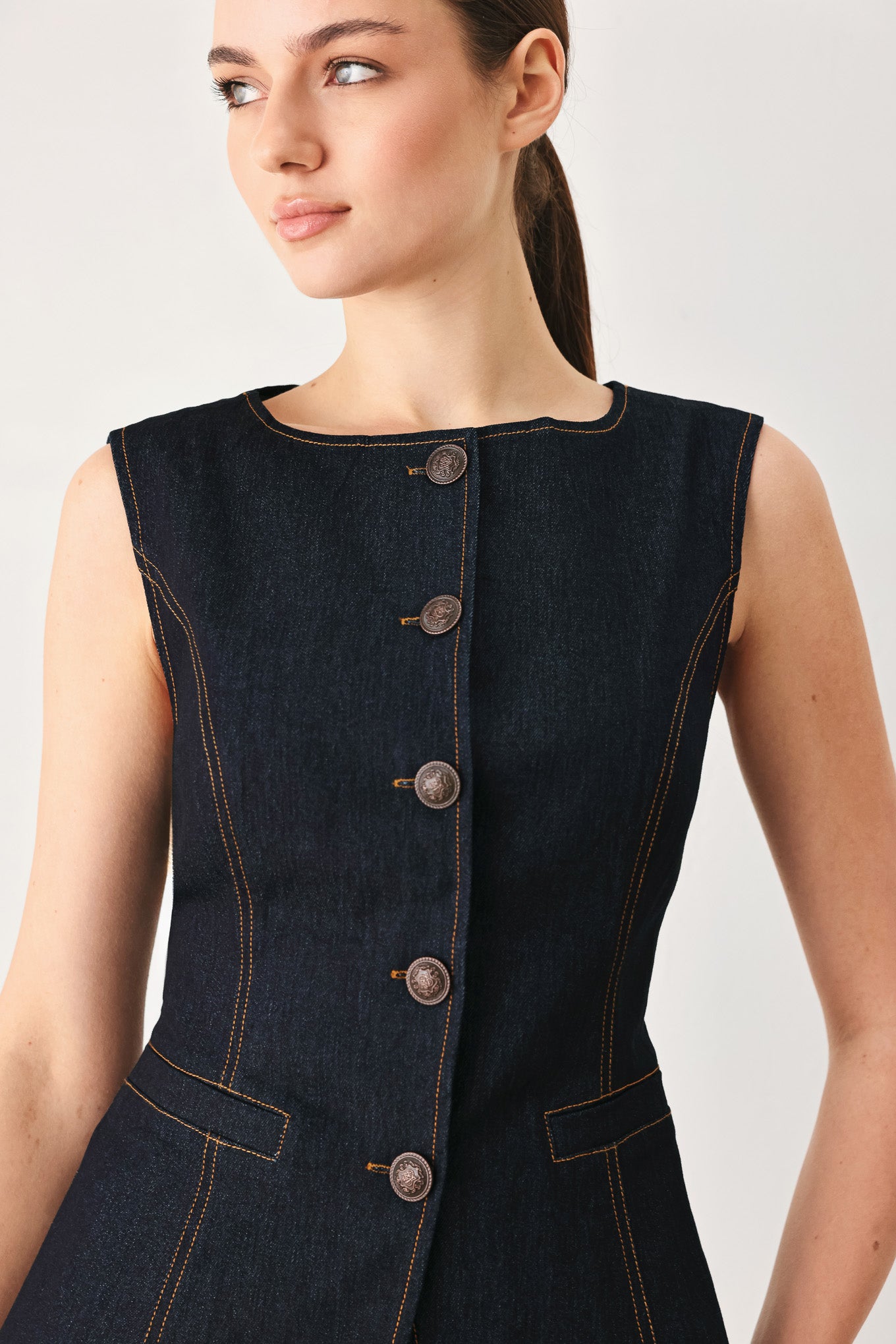 Woman wearing a dark denim vest with wide neckline and front button down | FREEMARKET