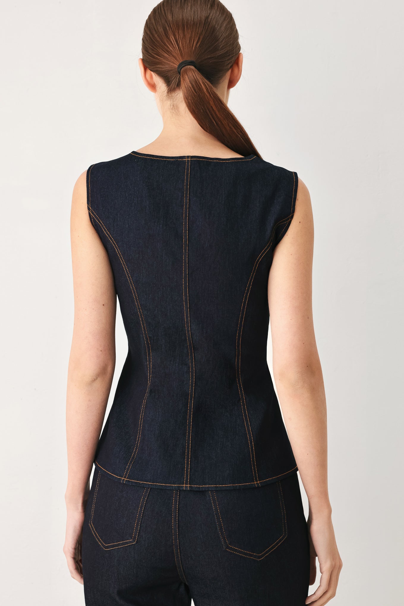 Woman wearing a dark denim vest with wide neckline and front button down | FREEMARKET
