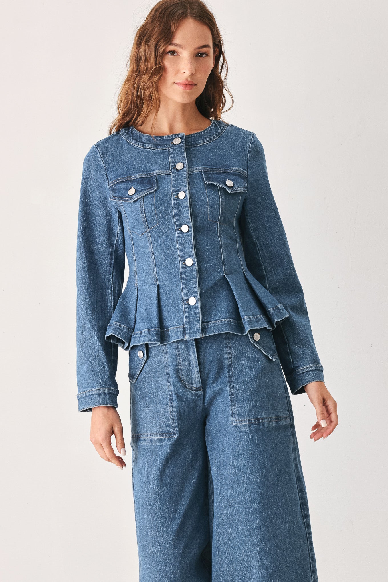 A woman wearing a cropped blue denim jacket with silver buttons and peplum waist | FREEMARKET