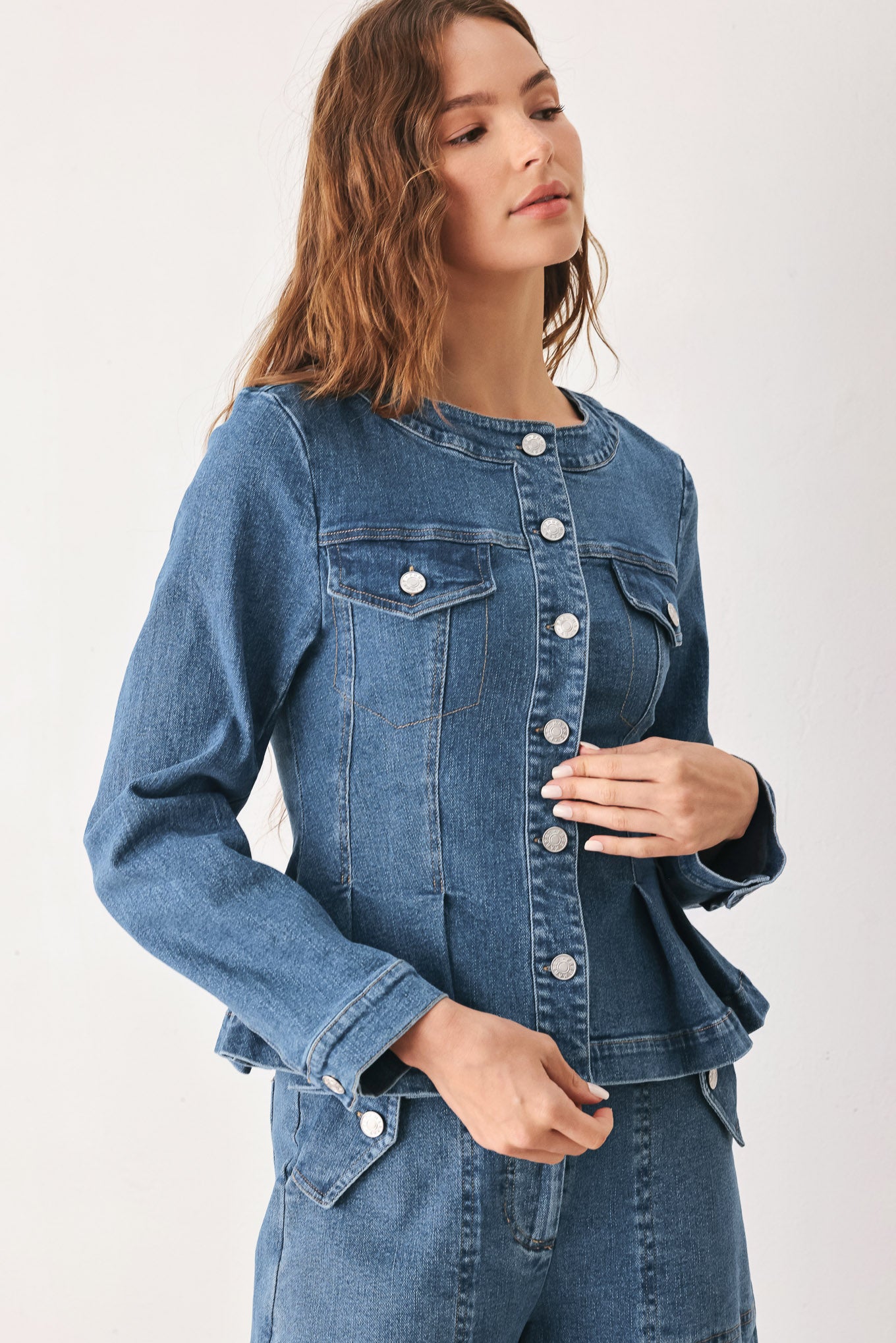 A woman wearing a cropped blue denim jacket with silver buttons and peplum waist | FREEMARKET