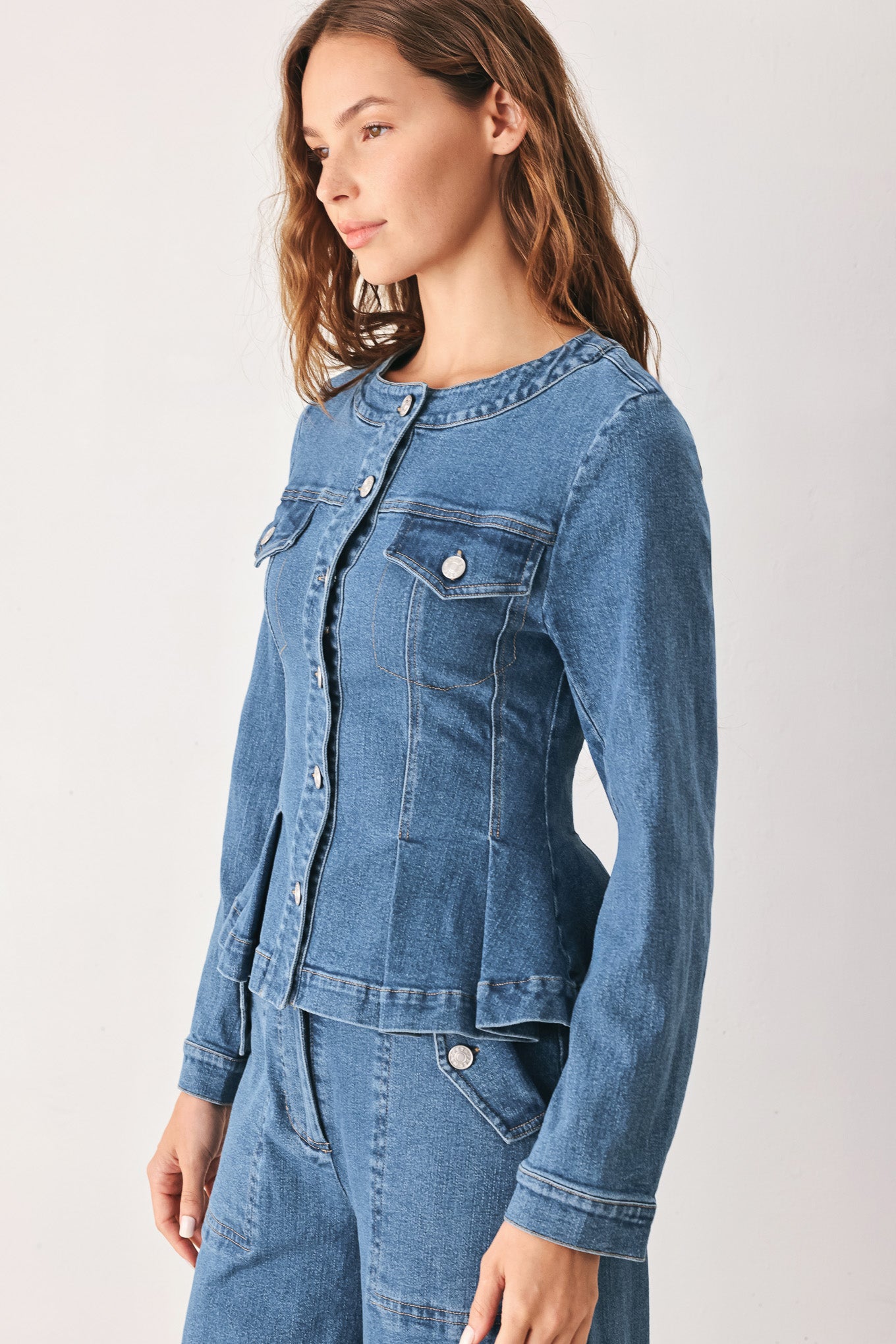 A woman wearing a cropped blue denim jacket with silver buttons and peplum waist | FREEMARKET