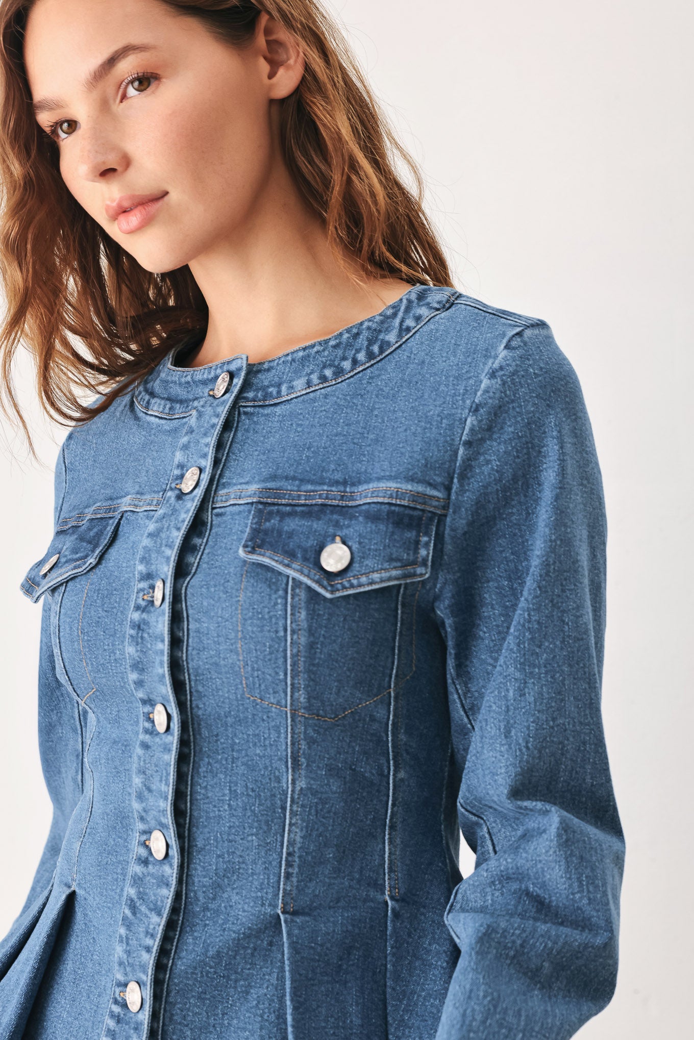A woman wearing a cropped blue denim jacket with silver buttons and peplum waist | FREEMARKET