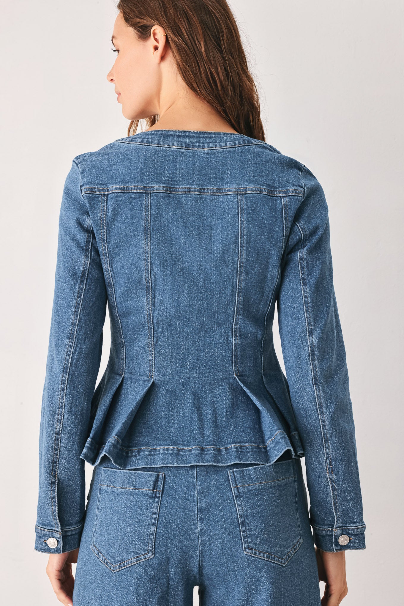 A woman wearing a cropped blue denim jacket with silver buttons and peplum waist | FREEMARKET