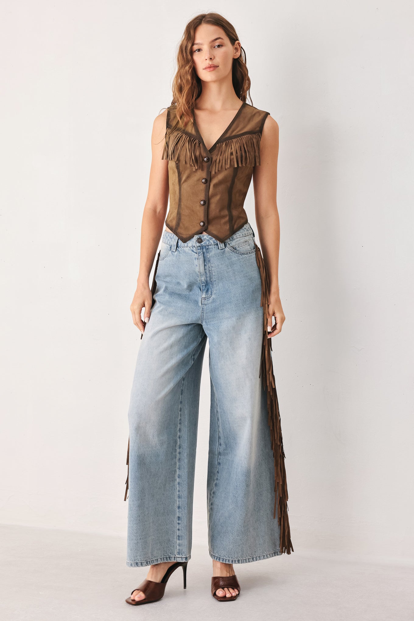 A woman modeling a brown faux-suede vest with fringe trim and button-front detailing | FREEMARKET