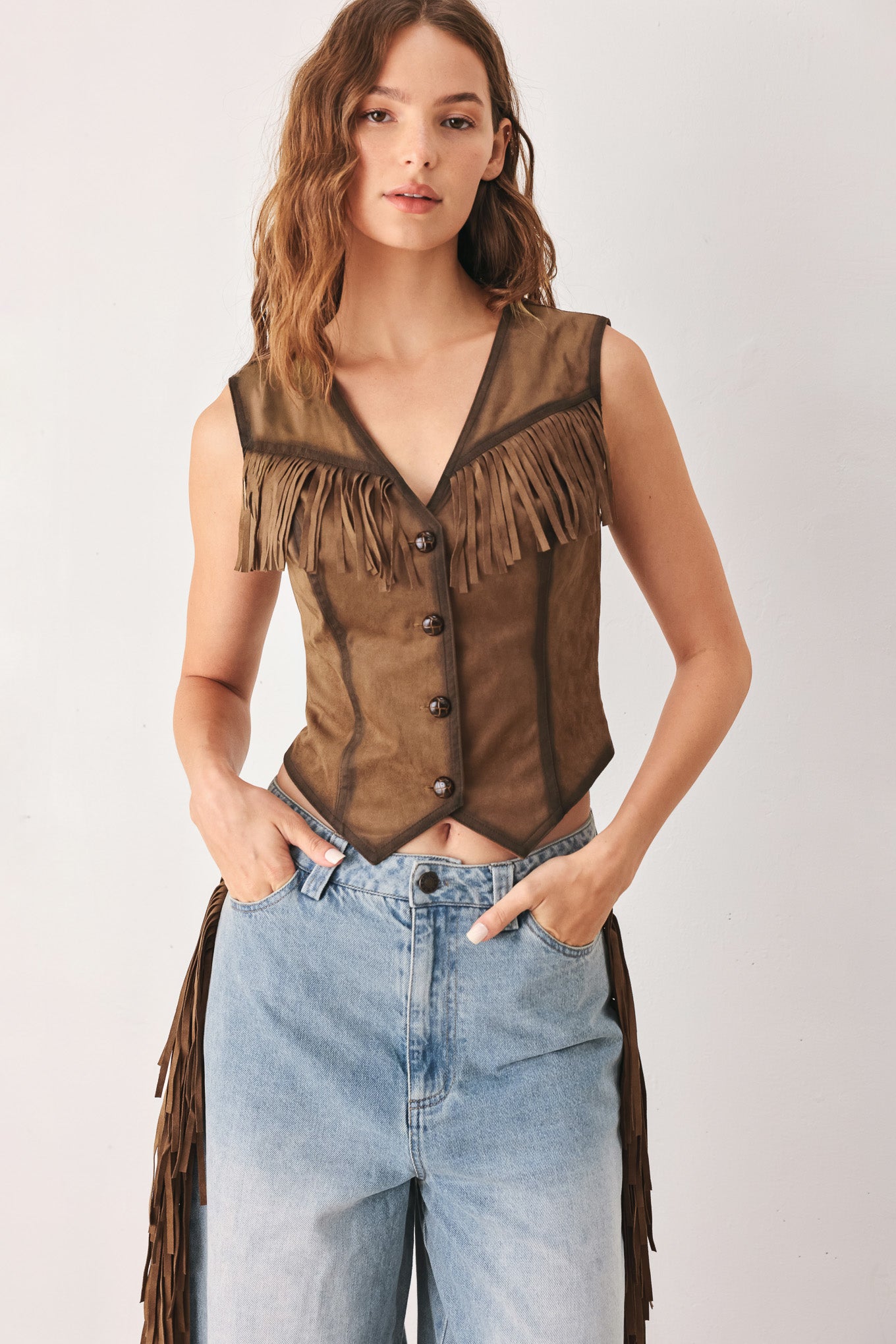 A woman modeling a brown faux-suede vest with fringe trim and button-front detailing | FREEMARKET