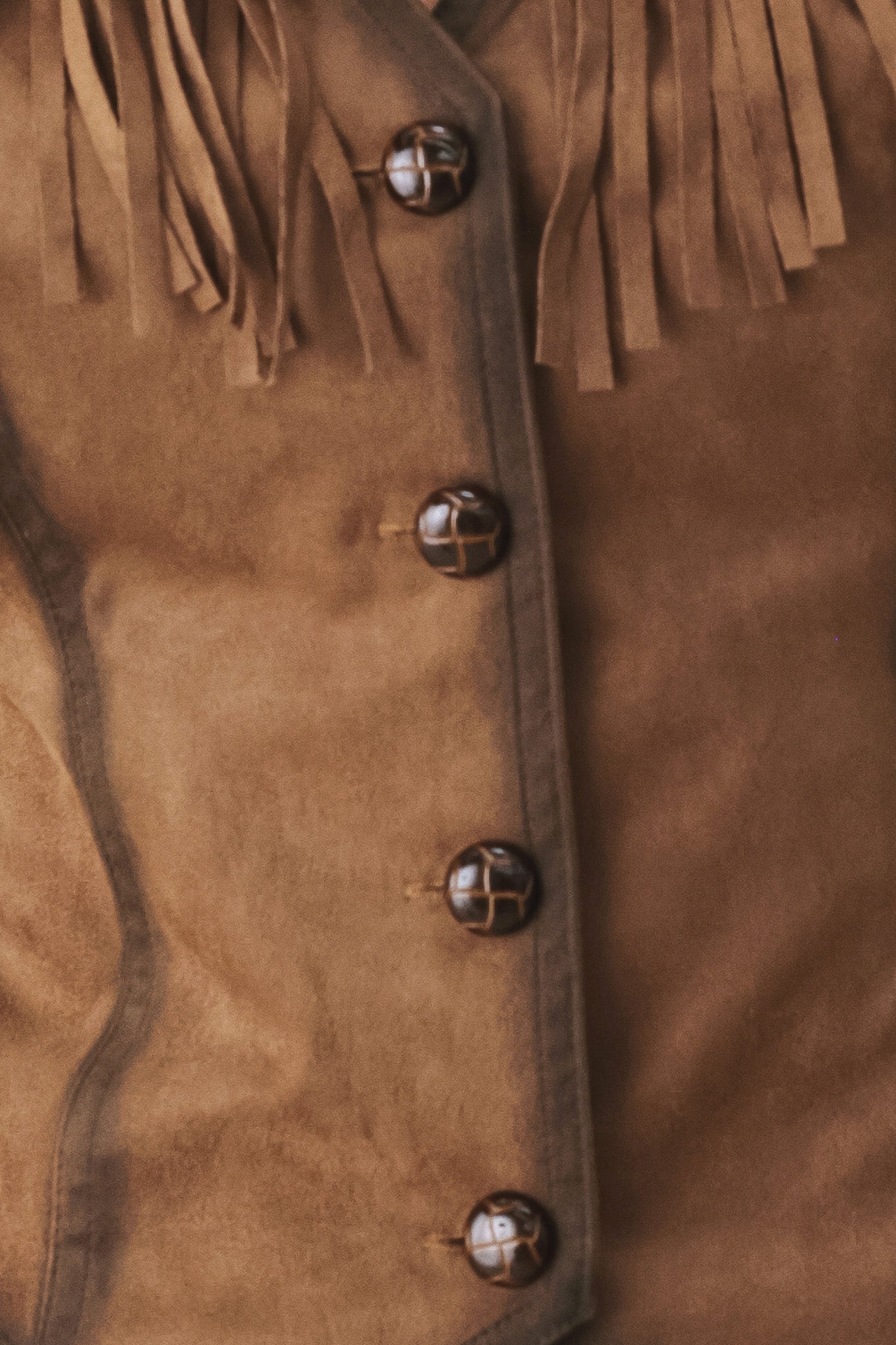 A woman modeling a brown faux-suede vest with fringe trim and button-front detailing | FREEMARKET