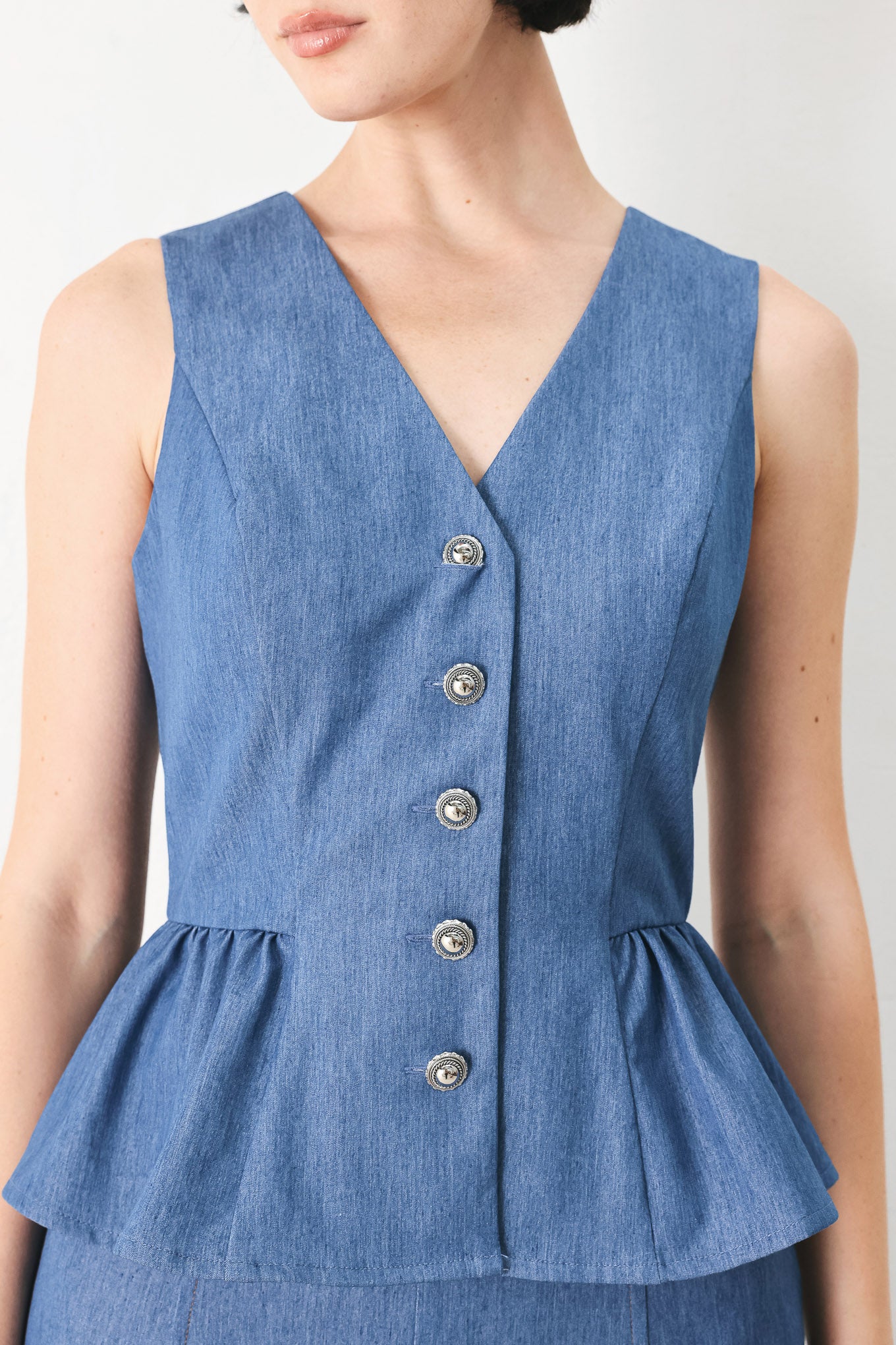Woman wearing woven blue vest with front closure, sleeveless and peplum | FREEMARKET