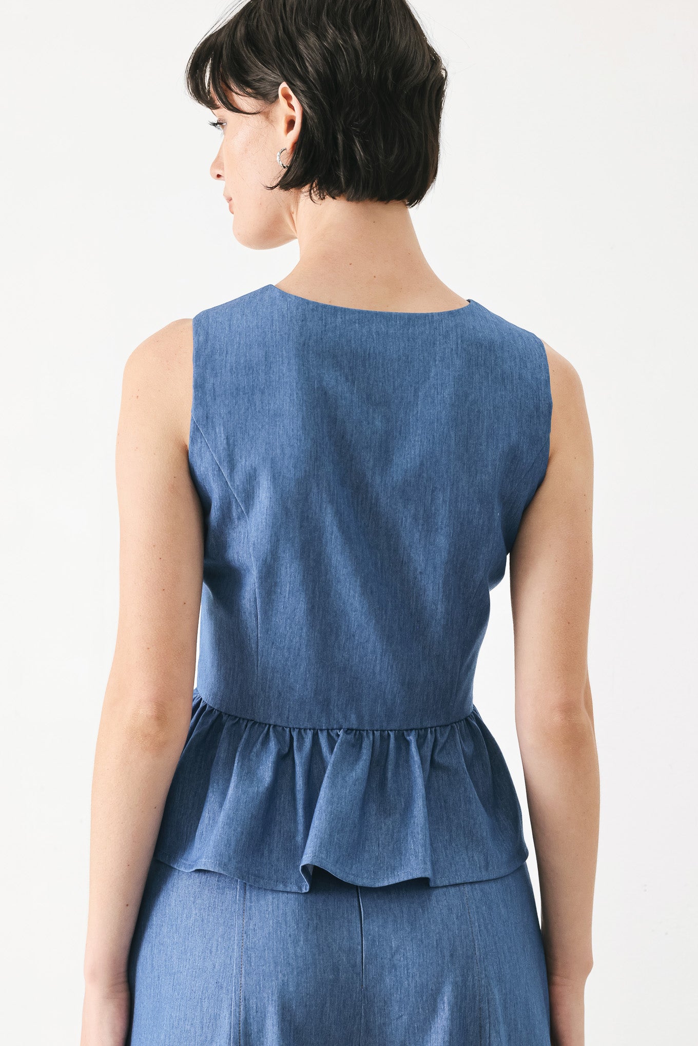 Woman wearing woven blue vest with front closure, sleeveless and peplum | FREEMARKET
