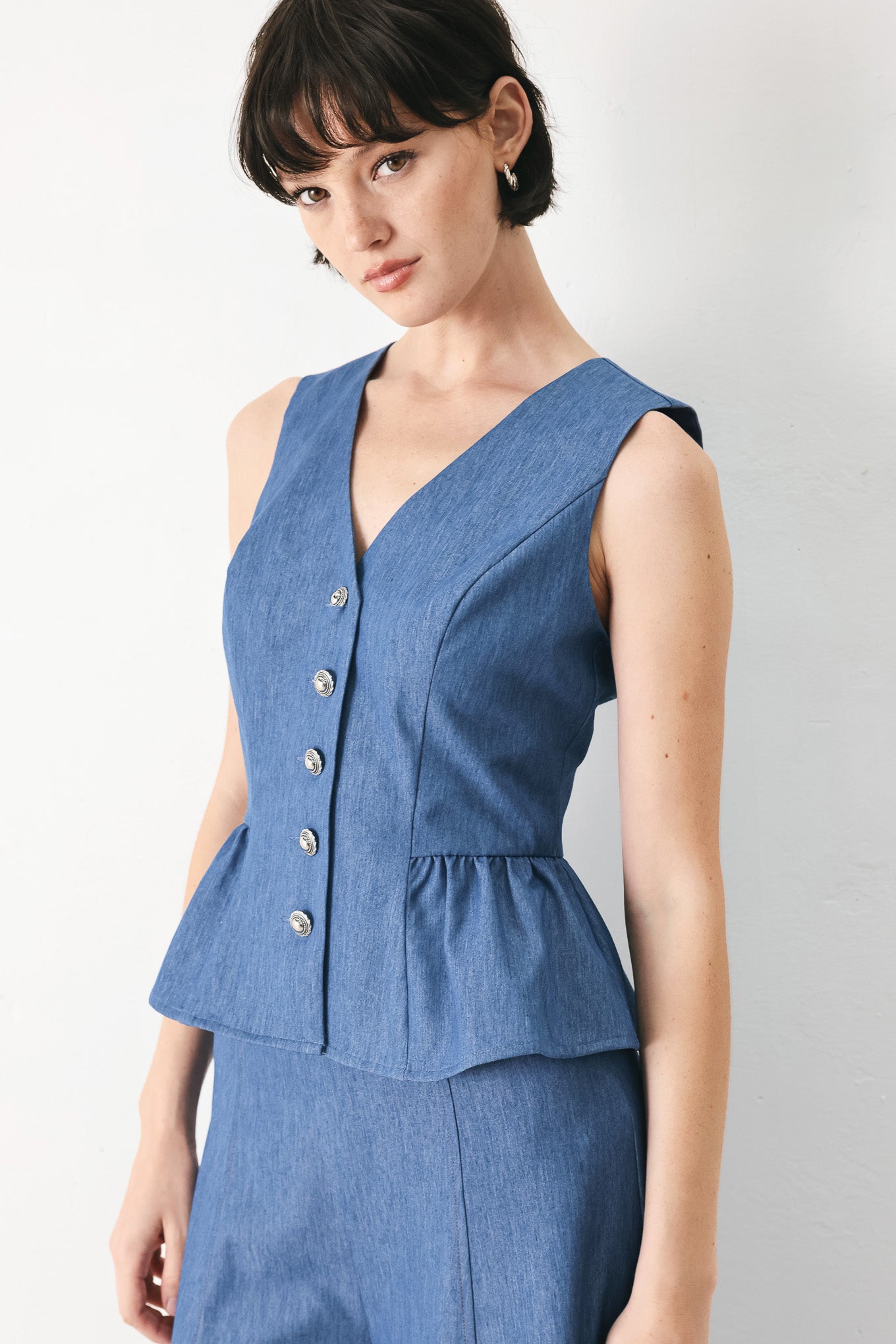 Woman wearing woven blue vest with front closure, sleeveless and peplum | FREEMARKET