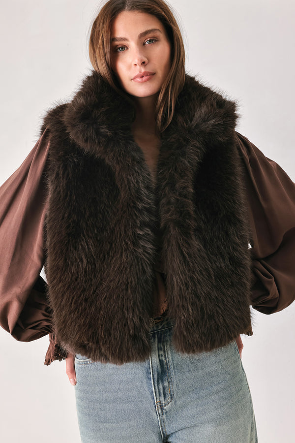 A model wearing a brown faux fur vest over a brown long-sleeve top, paired with wide-leg light blue jeans | FREEMARKET
