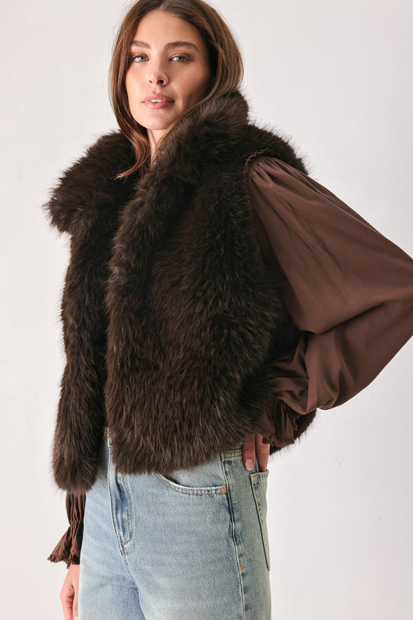 A model wearing a brown faux fur vest over a brown long-sleeve top, paired with wide-leg light blue jeans | FREEMARKET