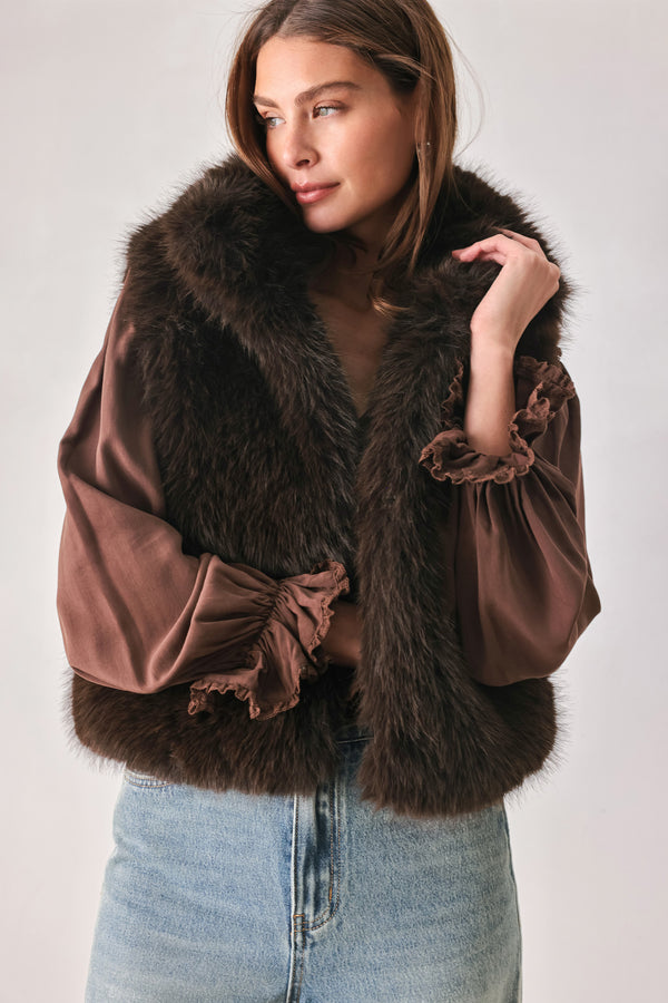A model wearing a brown faux fur vest over a brown long-sleeve top, paired with wide-leg light blue jeans | FREEMARKET