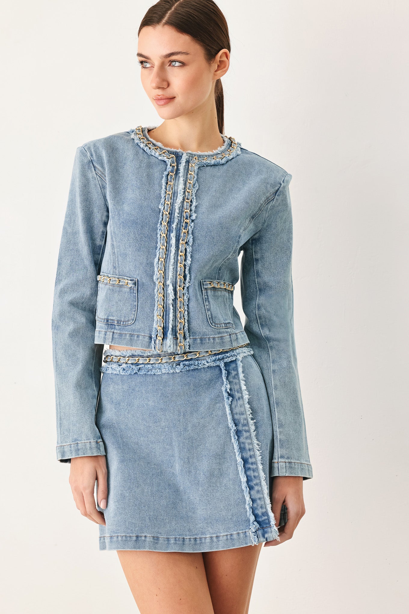 Woman wearing a light blue denim jacket featuring decorative gold chain trim and frayed details | FREEMARKET