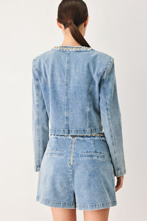 Woman wearing a light blue denim jacket featuring decorative gold chain trim and frayed details | FREEMARKET