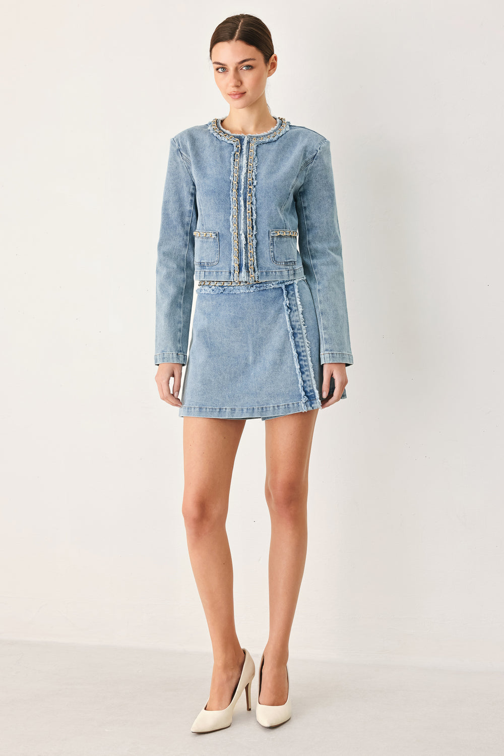 Woman wearing a light blue denim jacket featuring decorative gold chain trim and frayed details | FREEMARKET