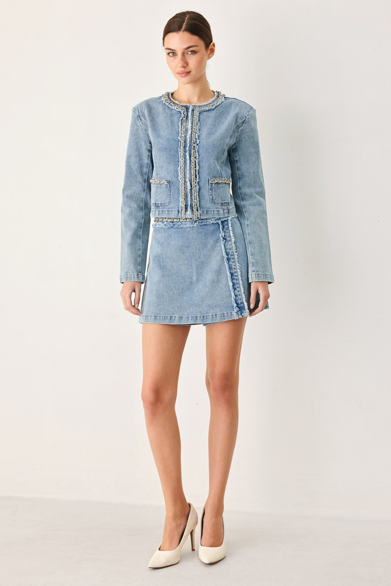 Woman wearing a light blue denim jacket featuring decorative gold chain trim and frayed details | FREEMARKET