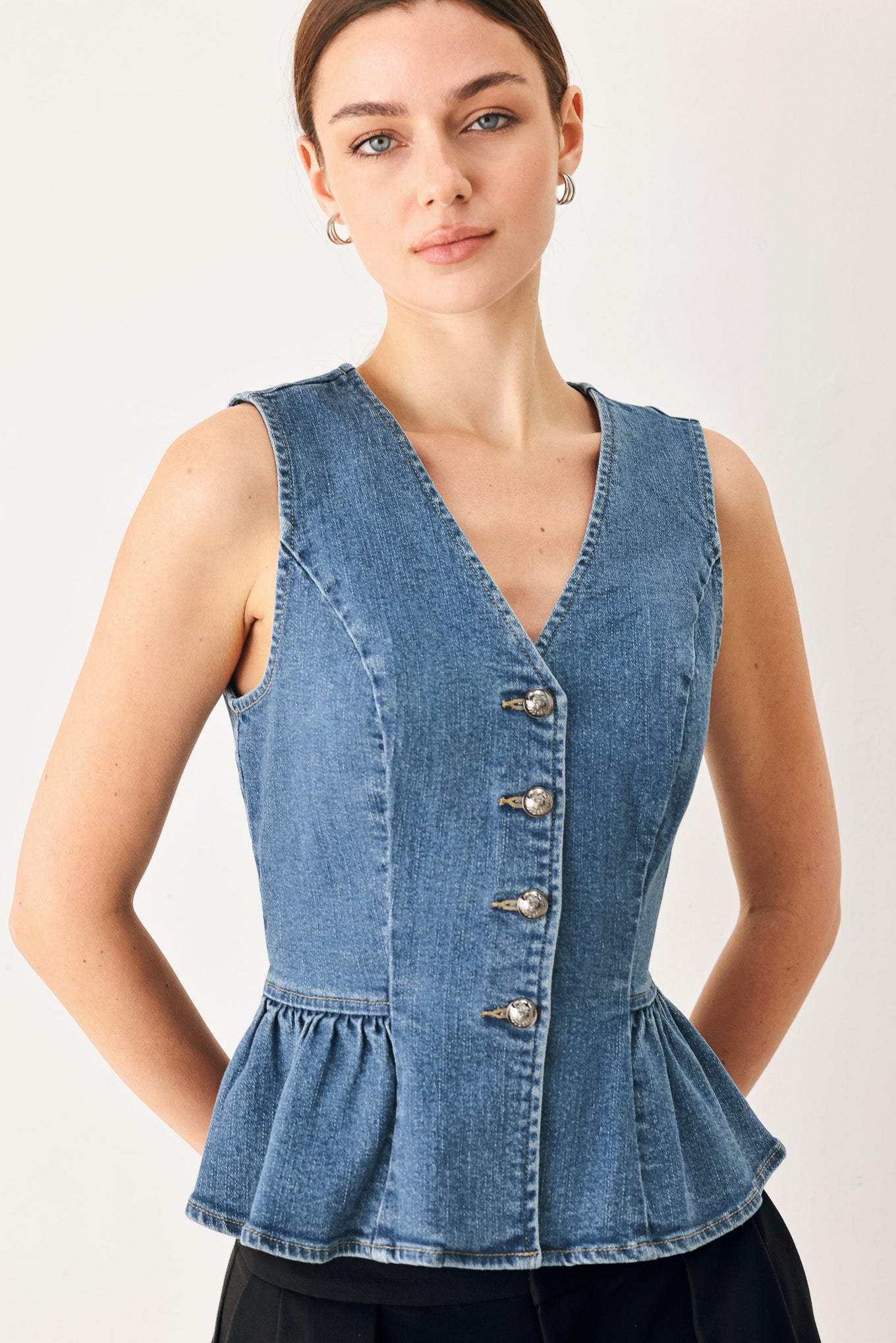 Woman wearing a denim peplum top on a white background